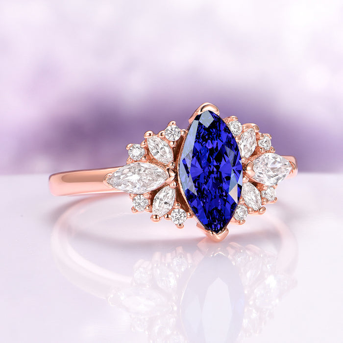 Adeline Marquise Cut Flower Blue Sapphire Engagement Ring in 14K Solid Rose Gold by Aquamarise Gold featuring a vibrant marquise blue sapphire with diamond accents on a rose gold band.