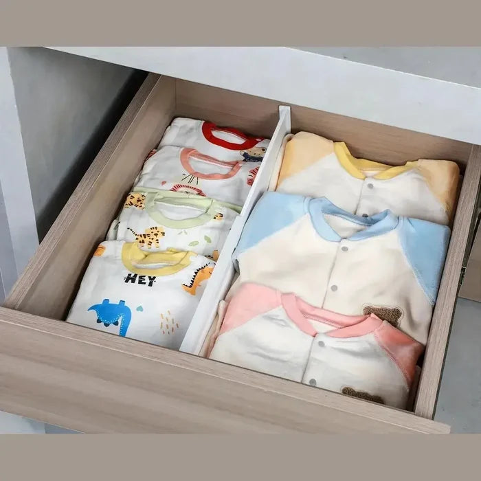 Organized baby clothing in a drawer, featuring adjustable drawer dividers for neat separation.
