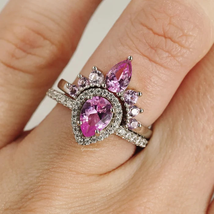 Amy Pink Sapphire Engagement Ring Set in Sterling Silver by Aquamarise featuring a pear-cut pink sapphire surrounded by smaller sapphires and diamond accents in a vintage-inspired design.