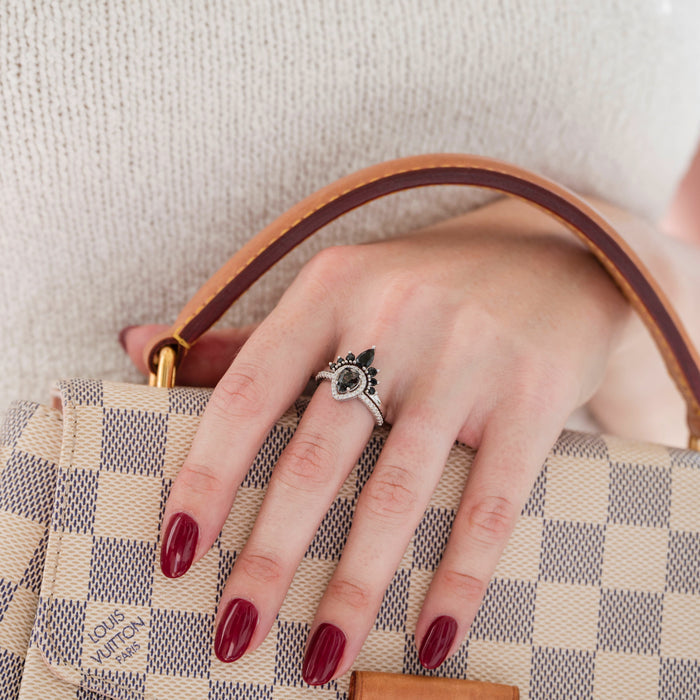 Amy Rutilated Quartz & Black Moissanite Engagement Ring Set in 14K White Gold by Aquamarise Gold, displayed on hand with deep red manicure holding a checked designer handbag.