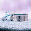 Crushed Aquamarine Leaf Wedding Band- 8MM Titanium featuring a polished titanium band engraved with delicate leaf motifs, paired with a silver ring adorned with sparkling aquamarine stones, showcasing elegant craftsmanship by Aquamarise.