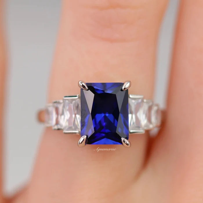 Art Deco Emerald Cut Blue Sapphire Engagement Ring in Sterling Silver by Aquamarise, featuring a rich blue emerald-cut sapphire center stone accented with tapered baguette clear gemstones on a polished sterling silver band, part of Sterling Silver Rings, September Birthstone Jewelry, Engagement Rings for Women, and Meaningful Jewelry Gifts collections.