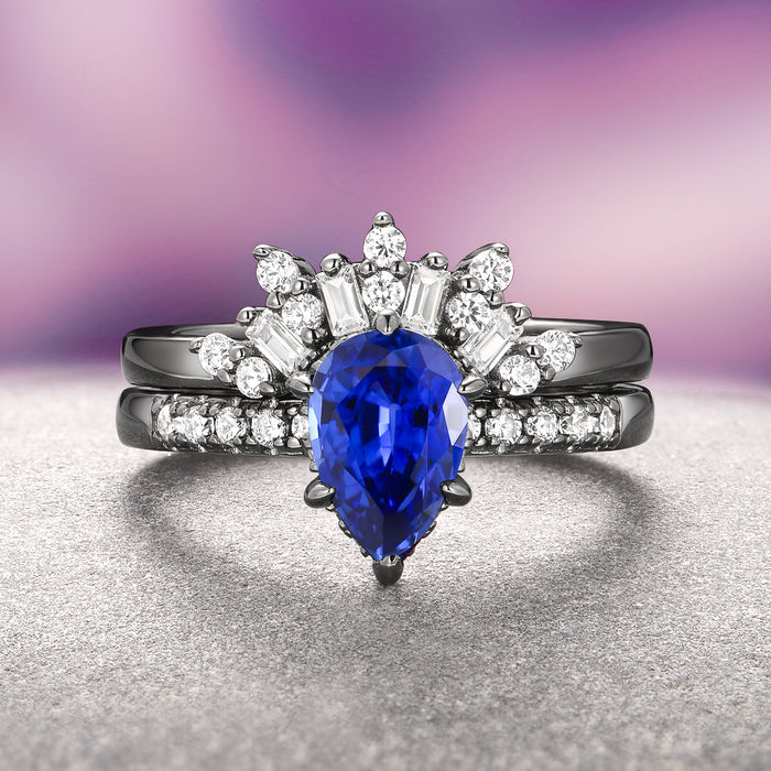 Art Deco Blue Sapphire Ring Set- Black Ruthenium features a teardrop-shaped blue sapphire centerpiece surrounded by baguette and round white gemstones on black ruthenium over sterling silver bands by Aquamarise, blending vintage glamour and modern elegance.