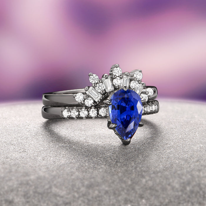 Art Deco Blue Sapphire Ring Set- Black Ruthenium from Aquamarise features a teardrop-shaped blue sapphire centerpiece accented by baguette and round white gemstones on a black ruthenium over sterling silver band, blending vintage charm with modern elegance.