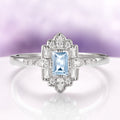 Art Deco Mosaic Aquamarine Engagement Ring in 14K White Gold by Aquamarise Gold, featuring an emerald-cut ice blue aquamarine surrounded by geometric diamond accents on a polished white gold band, part of Solid Gold Engagement Rings and March Birthstone Jewelry collections.