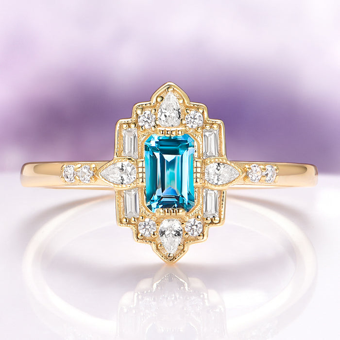 Art Deco London Blue Topaz Engagement Ring in 14K Solid Yellow Gold by Aquamarise Gold, featuring an emerald-cut blue topaz with diamond accents in a vintage-inspired design.