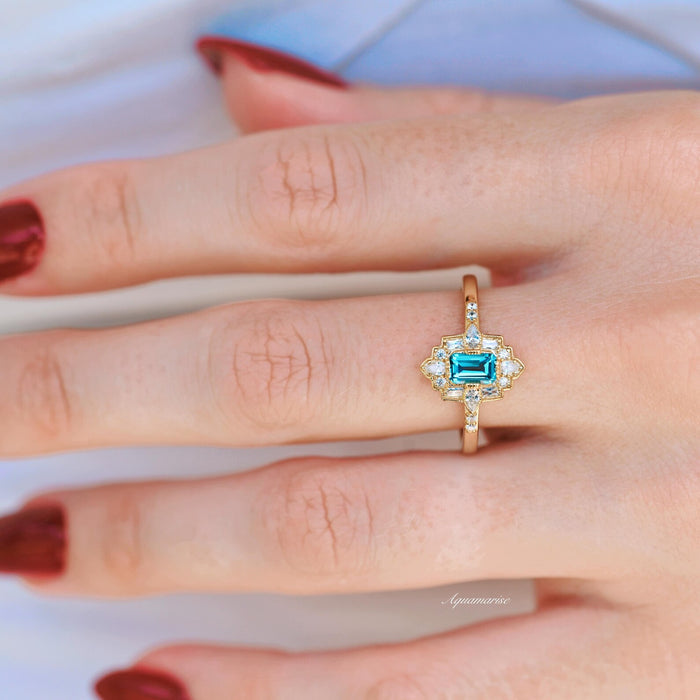 Art Deco London Blue Topaz Engagement Ring in 14K Solid Yellow Gold by Aquamarise Gold featuring an emerald-cut blue topaz with diamond accents in a vintage-inspired design.