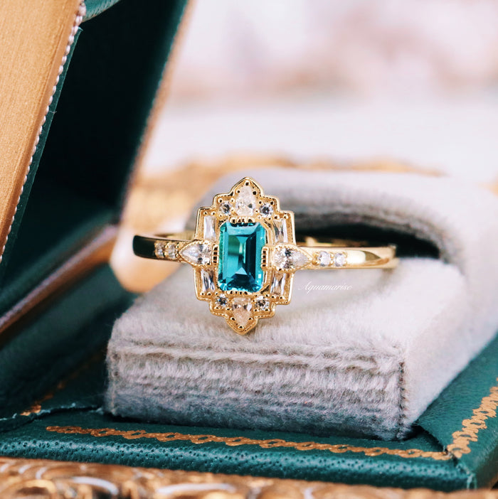 Art Deco London Blue Topaz Engagement Ring in 14K Solid Yellow Gold by Aquamarise Gold featuring an emerald-cut blue topaz with diamond accents in a vintage-inspired setting.