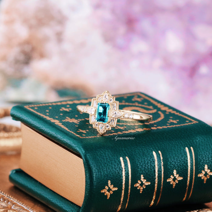 Art Deco London Blue Topaz Engagement Ring in 14K Solid Yellow Gold by Aquamarise Gold featuring a vibrant emerald-cut blue topaz with intricate vintage-inspired details.