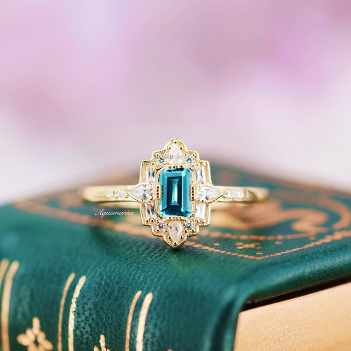 Art Deco London Blue Topaz Engagement Ring in 14K Solid Yellow Gold by Aquamarise Gold featuring an emerald-cut blue topaz with delicate diamond accents in a vintage-inspired design.