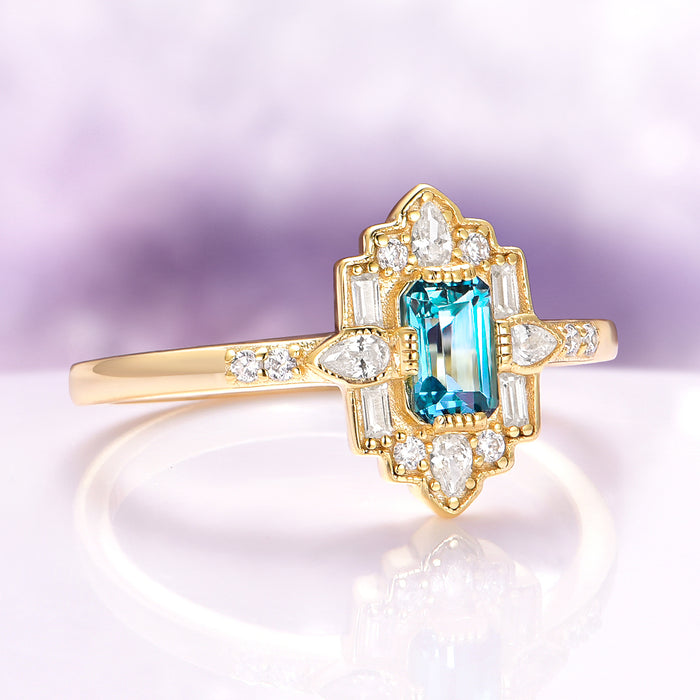 Art Deco London Blue Topaz Engagement Ring in 14K Solid Yellow Gold by Aquamarise Gold featuring an emerald-cut blue topaz surrounded by diamonds in a vintage-inspired setting.