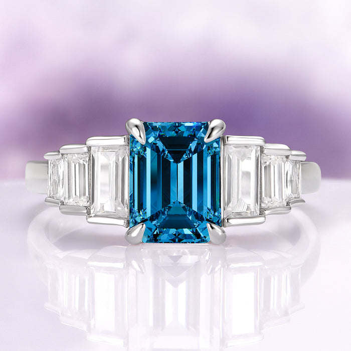 Art Deco Natural London Blue Topaz Engagement Ring in Sterling Silver by Aquamarise, featuring an emerald-cut deep blue topaz center stone flanked by tapered baguette clear gemstones on a polished sterling silver band, perfect for Sterling Silver Rings, November Birthstone, Engagement Rings for Women, and Birthstone Jewelry collections.