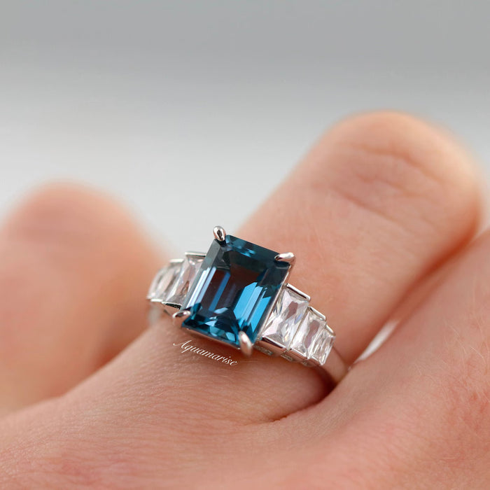 Art Deco Natural London Blue Topaz Engagement Ring in Sterling Silver by Aquamarise, showcasing a striking emerald-cut London blue topaz center stone with tapered baguette clear gemstones on a polished sterling silver band, part of Sterling Silver Rings, November Birthstone, and Engagement Rings for Women collections.