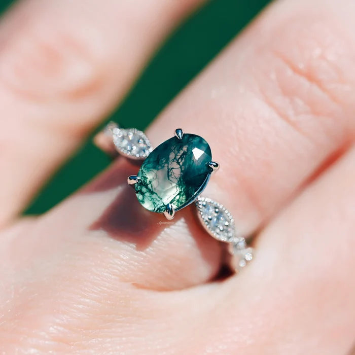 Art Deco Natural Moss Agate Ring in Sterling Silver by Aquamarise, featuring an oval moss agate stone with intricate silver detailing on a hand against a green background.