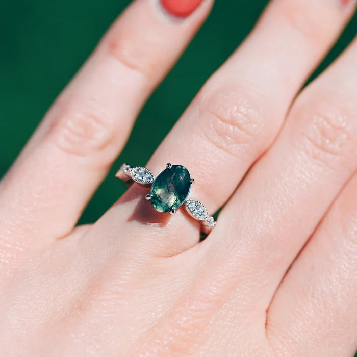 Art Deco Natural Moss Agate Ring in Sterling Silver by Aquamarise, featuring an oval moss agate stone with diamond accents on an intricate sterling silver band worn on a hand.