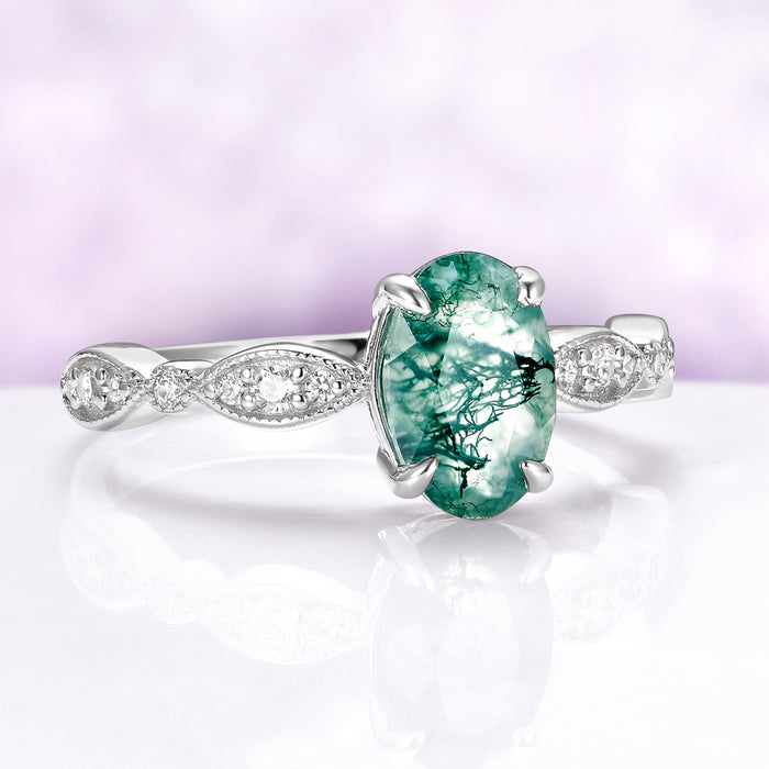 Ring with a green gemstone and silver band on a white background