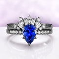 Art Deco Pear Blue Sapphire Ring Set in Black Ruthenium by Aquamarise featuring a pear-shaped blue sapphire with diamond accents on elegant black ruthenium bands.