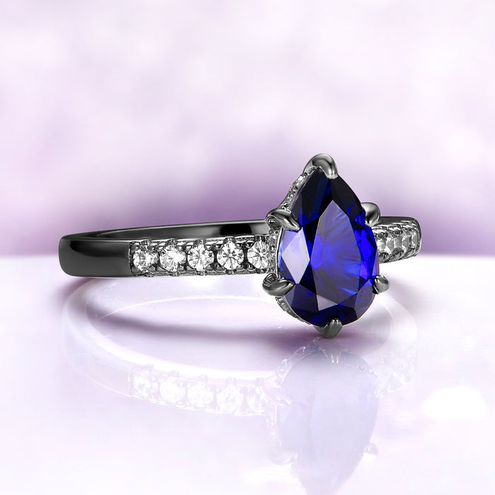 Art Deco Pear Blue Sapphire Ring Set in Black Ruthenium by Aquamarise, featuring a pear-shaped blue sapphire and sparkling diamonds on a black ruthenium band.