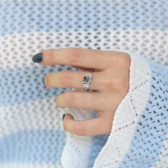 Art Deco Rutilated Quartz Engagement Ring in Sterling Silver by Aquamarise, showcasing a unique rutilated quartz center with detailed sterling silver band, styled on hand with blue and white knit sweater.
