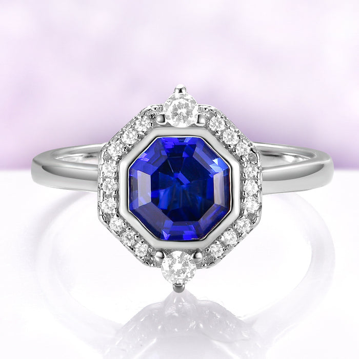 Asscher Cut Art Deco Bezel Set Blue Sapphire Ring in Sterling Silver by Aquamarise, featuring a deep blue sapphire surrounded by a diamond halo on a sleek silver band.