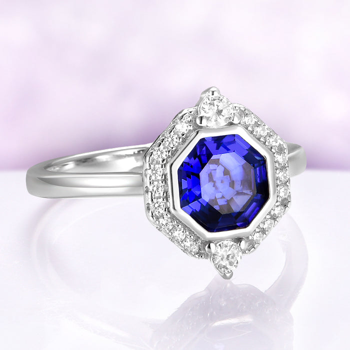 Asscher Cut Art Deco Bezel Set Blue Sapphire Ring in Sterling Silver by Aquamarise, featuring a deep blue sapphire surrounded by sparkling diamonds on a polished silver band.