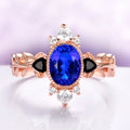 Aurelia Sapphire & Black Onyx Leaf Engagement Ring in 14K Solid Rose Gold by Aquamarise Gold, featuring an oval sapphire, black onyx accents, white gemstones, and a rose gold leaf-inspired band.