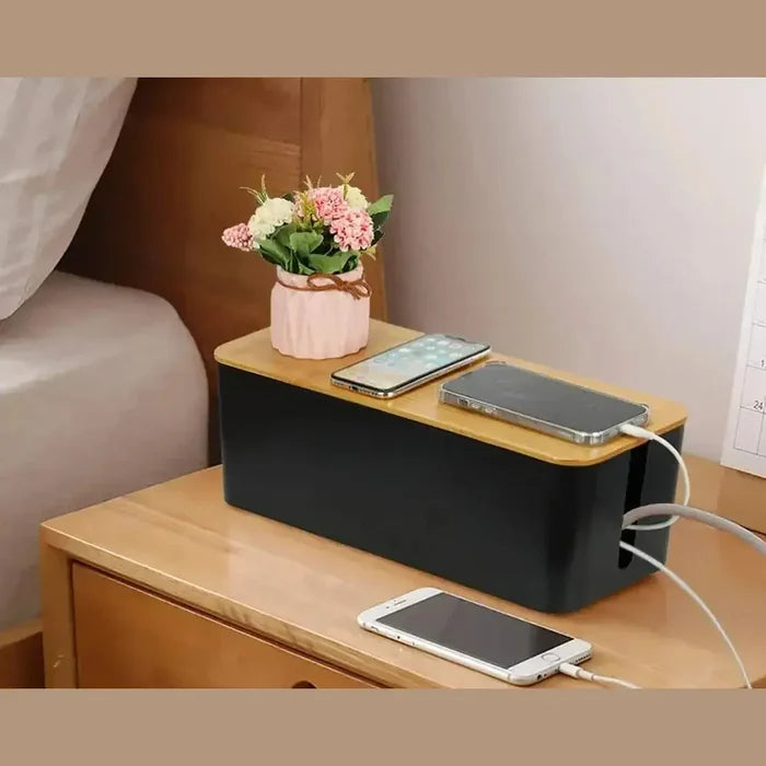 Bamboo cable organizer box on a bedside table, storing phones and a small plant for tidy decor.