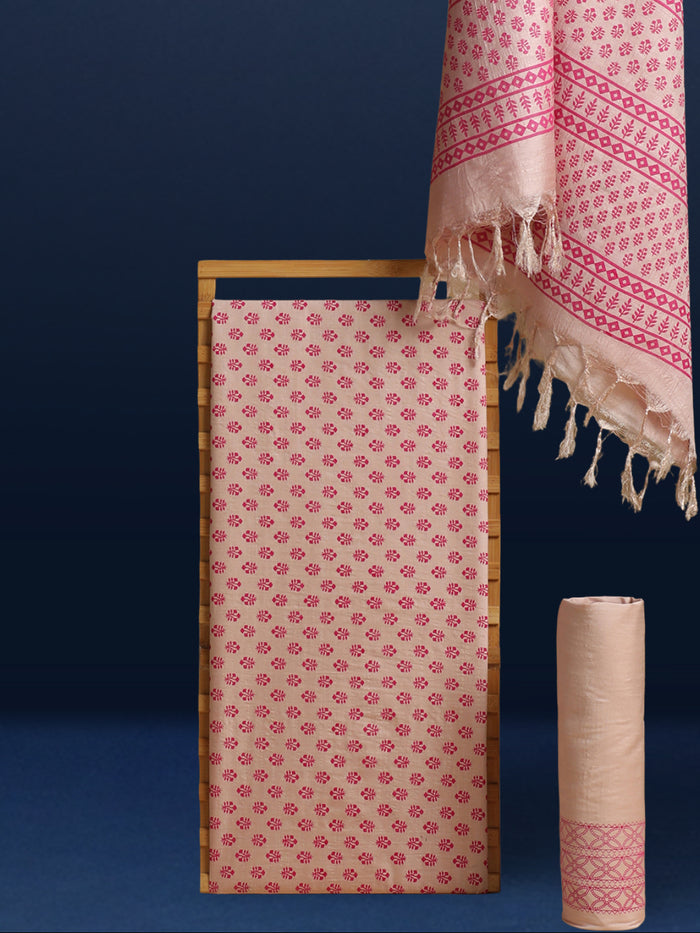 Beige katan silk unstitched suit set with small magenta floral hand block print, linear geometric striped borders and tasselled dupatta ends.