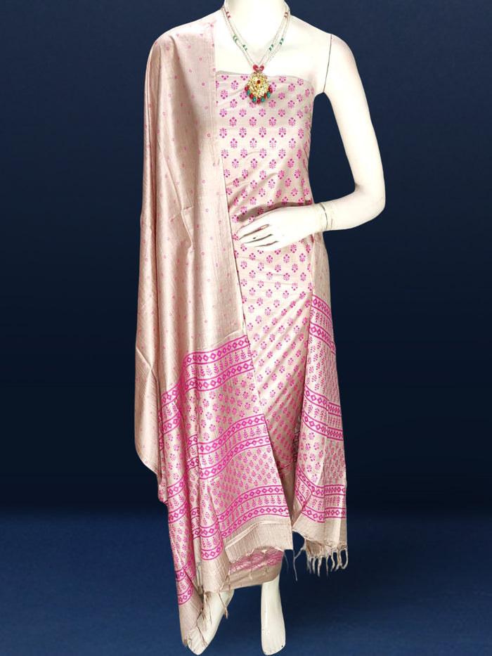 Beige katan silk unstitched suit set with small magenta floral hand block print, linear geometric striped borders and tasselled dupatta ends.