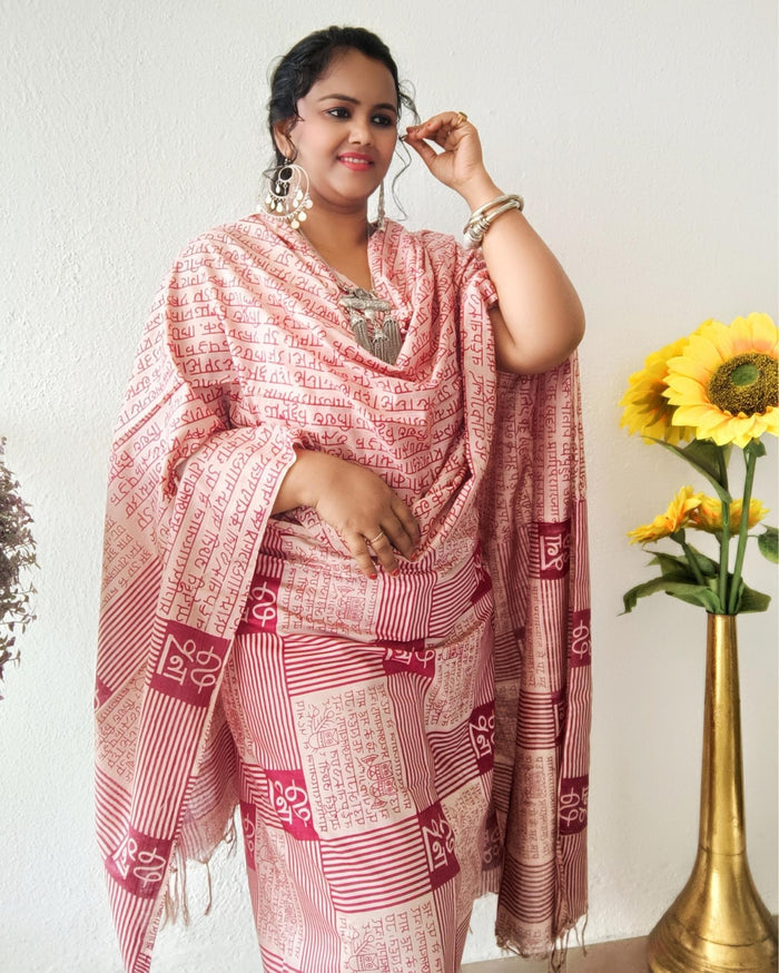 Beige Katan silk unstitched suit set block printed with panels of Sanskrit calligraphy in deep magenta, separated by linear stripes with white accents and straight, clean edges.