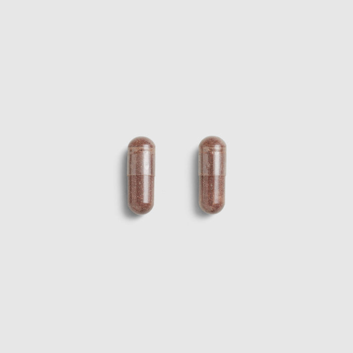 Two brown Juice Plus+ Capsules on a light gray background