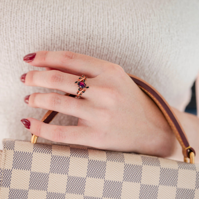 Black Fire Opal & Onyx Leaf Ring in 14K Rose Gold Vermeil worn on a hand with deep red nail polish, showcasing a marquise-shaped black fire opal surrounded by black onyx stones in a delicate rose gold vermeil band, presented by Aquamarise.