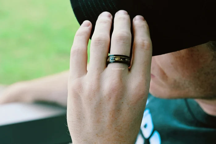Black Onyx & Meteorite Gold Leaf Couples Ring Set featuring black gemstone and gold leaf details, styled on hand near face with black hat, by Aquamarise in nature setting.