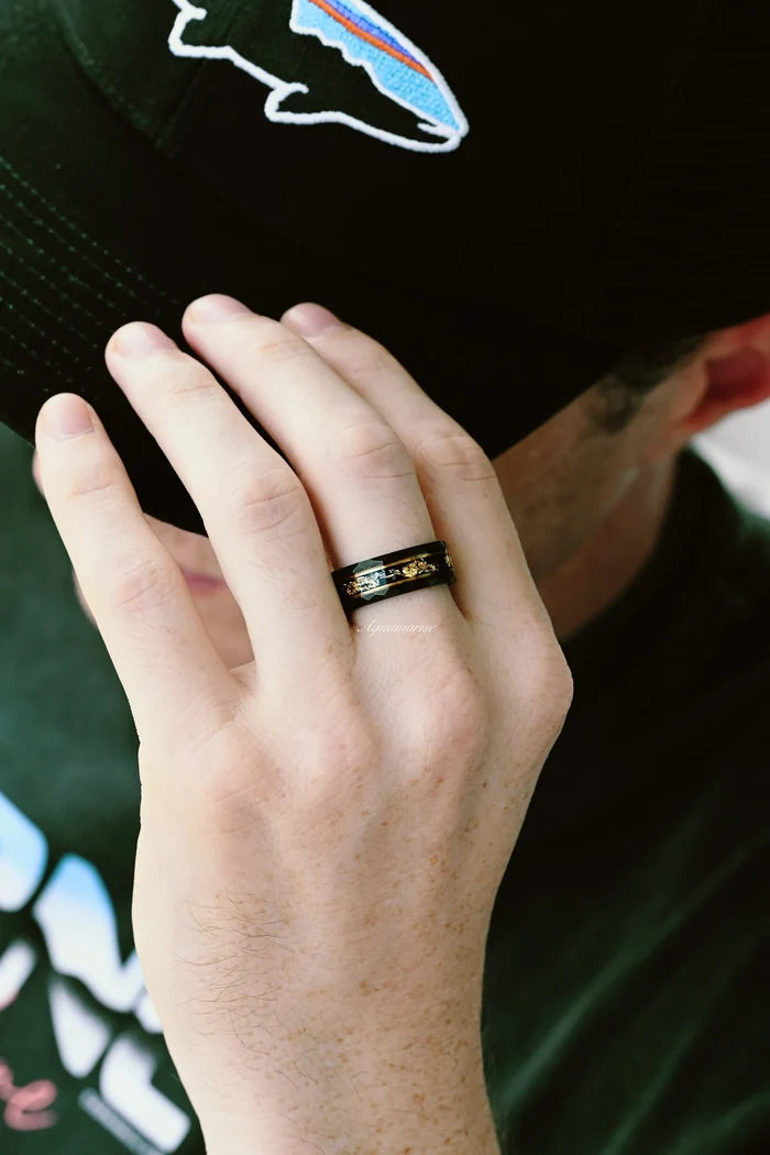 Black Onyx & Meteorite Gold Leaf Couples Ring Set featuring a black band with gold leaf and meteorite accents, worn on a hand near a black cap by Aquamarise in a casual setting.