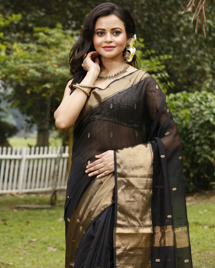 Black Maheshwari silk saree with small gold buti across a semi-sheer body and a wide decorative gold border, handwoven in Maheshwar