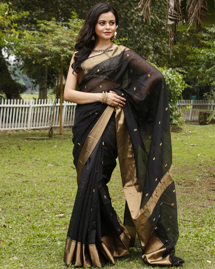 Black Maheshwari silk saree with small gold buti across a semi-sheer body and a wide decorative gold border, handwoven in Maheshwar