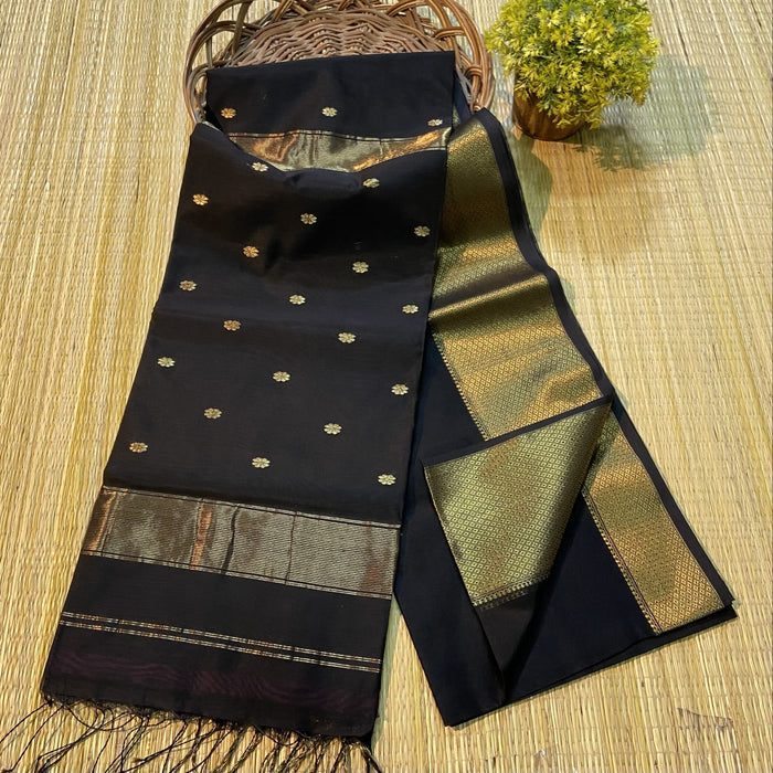 Black Maheshwari silk saree with small gold buti across a semi-sheer body and a wide decorative gold border, handwoven in Maheshwar
