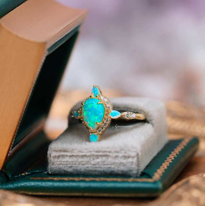 Blue Fire Opal Engagement Ring- 14K Solid Yellow Gold with teardrop and pear-shaped blue fire opals and diamond accents, elegantly presented in a vintage-inspired jewelry box by Aquamarise Gold