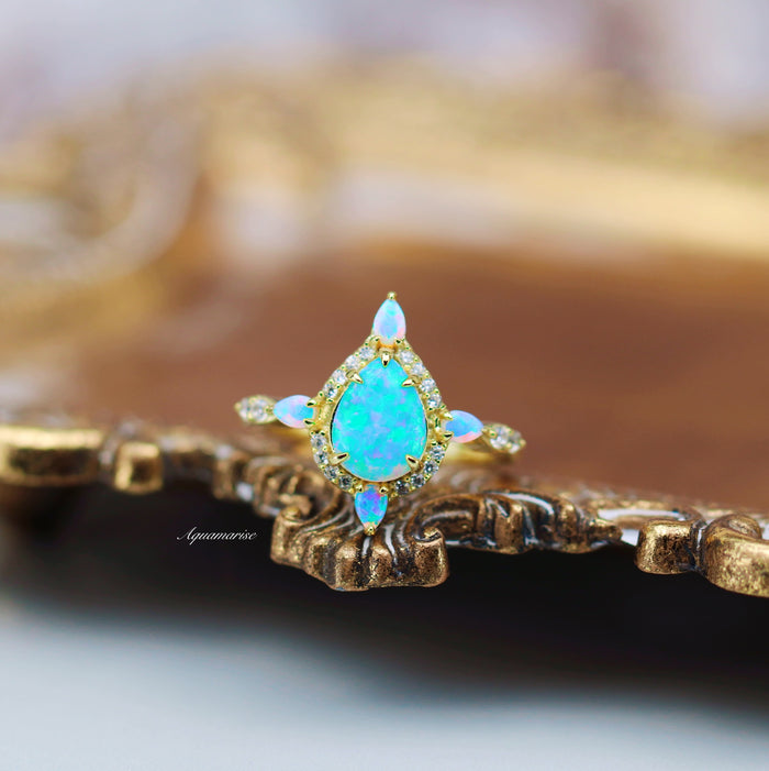 Blue Fire Opal Engagement Ring- 14K Solid Yellow Gold showcasing a teardrop blue fire opal with diamond accents, crafted by Aquamarise Gold in a delicate, fantasy-inspired design.