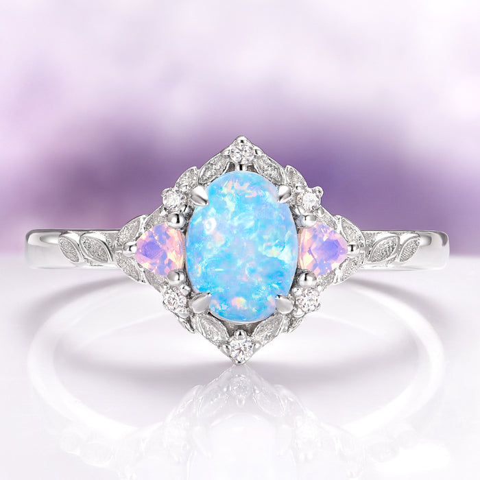 Blue Fire Opal & Opalescent Sapphire Leaf Engagement Ring in Sterling Silver by Aquamarise featuring an oval blue fire opal with glowing sapphire accents and delicate leaf details on the band.