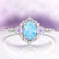 Blue Fire Opal & Opalescent Sapphire Leaf Engagement Ring in Sterling Silver by Aquamarise featuring an oval blue fire opal with glowing sapphire accents and delicate leaf details on the band.