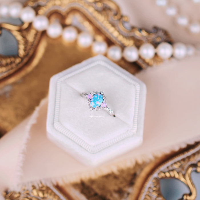 Blue Fire Opal & Opalescent Sapphire Leaf Engagement Ring in Sterling Silver displayed on a white velvet hexagon box, surrounded by elegant gold and pearl accents.