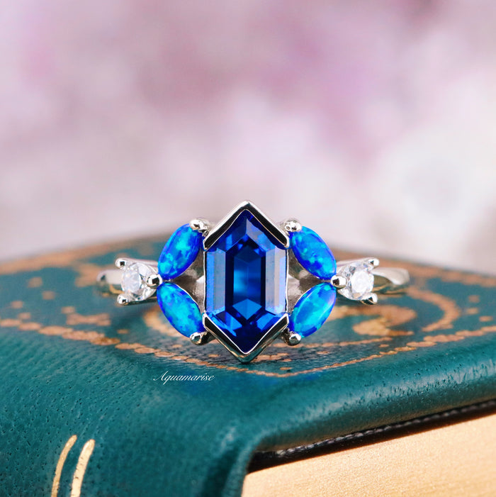 Blue Fire Opal & Sapphire Couples Ring Set by Aquamarise featuring a central sapphire with marquise blue fire opals and delicate diamond accents in a celestial-inspired silver band design.