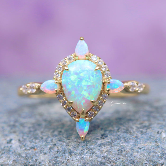 Blue Fire Opal & Crushed Diamond Couples Ring Set featuring a pear-shaped blue fire opal center surrounded by crushed diamonds and accented with marquise blue fire opals on a delicate gold band, crafted by Aquamarise.