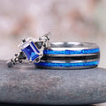 Blue Sapphire & Fire Opal Couples Ring Set by Aquamarise featuring a blue sapphire with black onyx accents and a matching band with vibrant blue fire opal inlays symbolizing love and commitment.