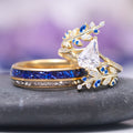Blue Sapphire & Fantasy Shield Cut Diamond (CZ) Couples Ring Set by Aquamarise featuring yellow gold bands with a unique shield cut cubic zirconia, accented by vibrant blue sapphires and sparkling white stones in an intricate, nature-inspired design.