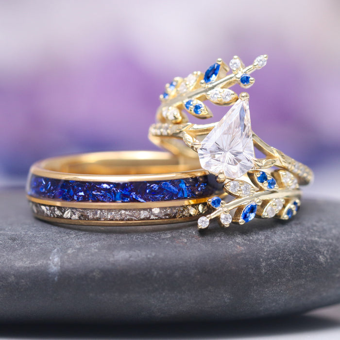 Blue Sapphire & Fantasy Shield Cut Diamond (CZ) Couples Ring Set by Aquamarise featuring yellow gold bands with a unique shield cut cubic zirconia, accented by vibrant blue sapphires and sparkling white stones in an intricate, nature-inspired design.