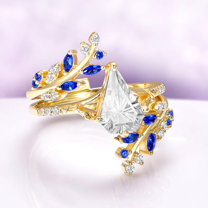Blue Sapphire & Fantasy Shield Cut Diamond Couples Ring Set by Aquamarise featuring yellow gold bands with marquise blue sapphires and shield-cut diamond CZ in a nature-inspired design.
