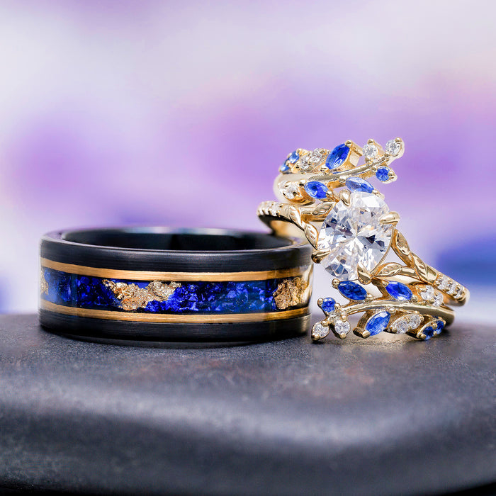 Lab-Grown Diamond & Sapphire Leaf Engagement Ring Set in 14K Solid Yellow Gold (IGI Certified) alongside a black tungsten band with blue sapphire and gold leaf inlay by Aquamarise Gold.