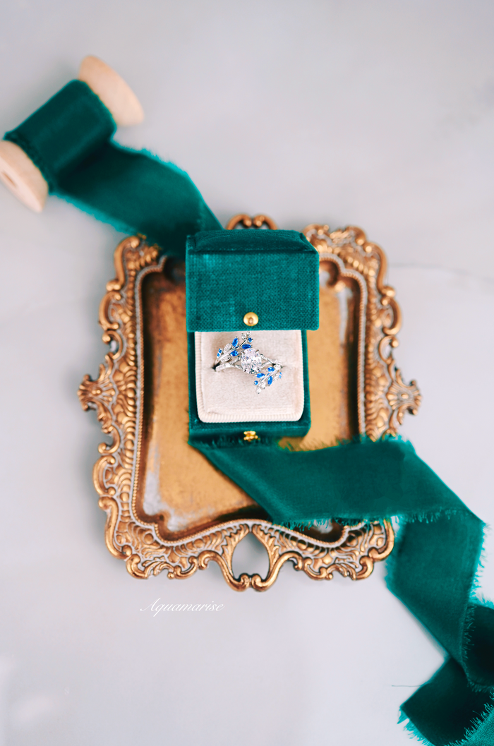 Blue Sapphire & Simulated Diamond Leaf Engagement Ring Set in Sterling Silver displayed in a green velvet box atop an ornate vintage gold tray with coordinating green ribbon by Aquamarise.